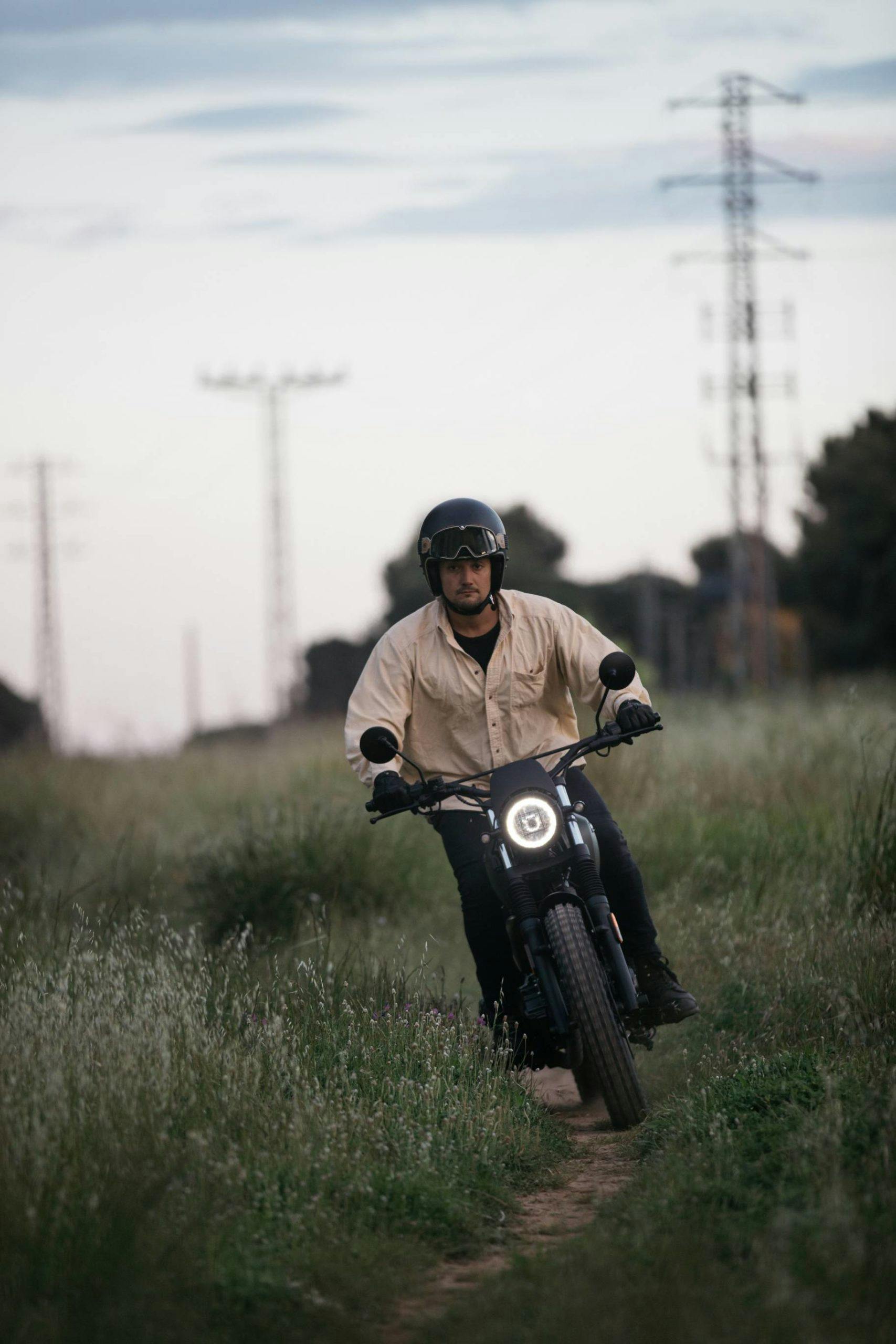 Brixton Motorcycles Felsberg 125 in Cargo Green driven on a narrow field path with the headlight on