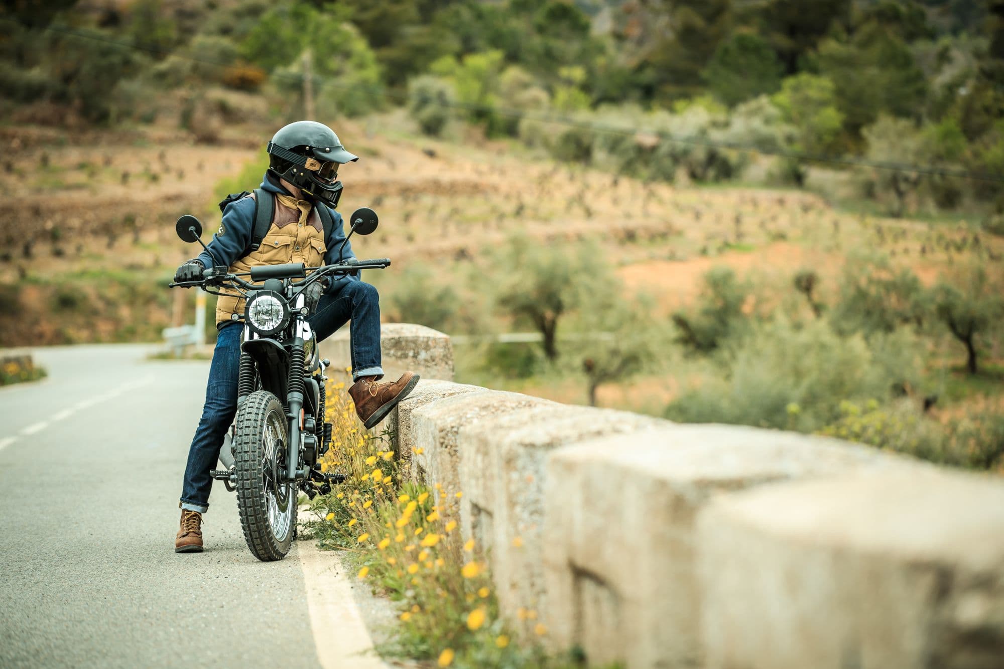 Rider sitting on a Felsberg 125 XC in Quick Silver, looking over the edge of a bridge