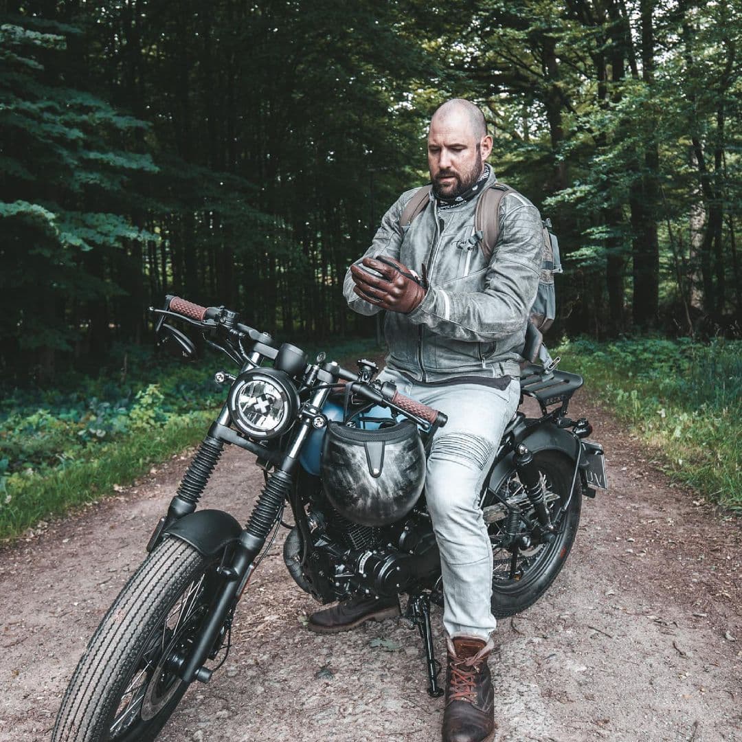 Rider of the Month Kev sitting on his Brixton Rayburn 125 in Royal Blue Matt / Horizon Blue Matt on a forest road surrounded by trees