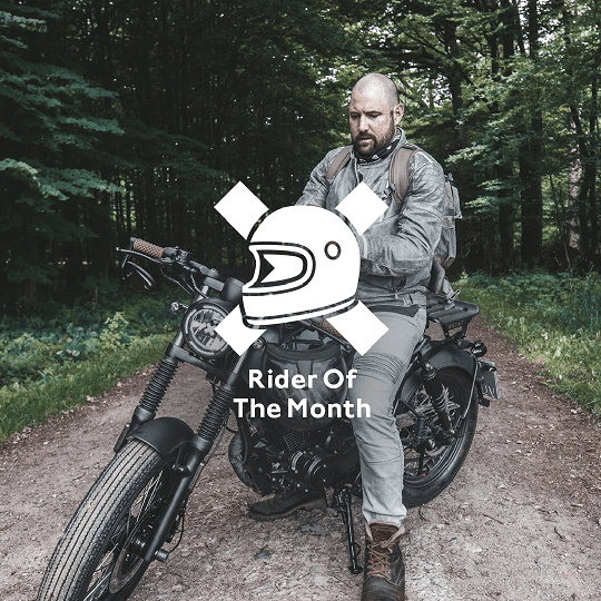 Rider of the Month Kev sitting on his Brixton Rayburn 125 in Royal Blue Matt / Horizon Blue Matt on a forest road surrounded by trees