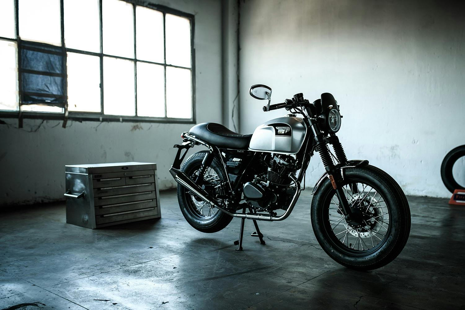 The Brixton Sunray 125 in Bullet Silver shown from the right side parked in a garage, lifestyle studio photo