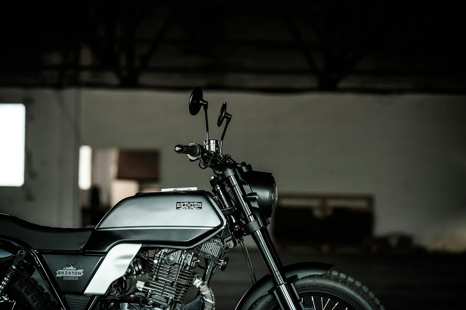 Seitliche Ansicht einer Brixton Motorcycles Felsberg 250 in Timberwolf Grey mit Fokus auf den Tank und Lenker