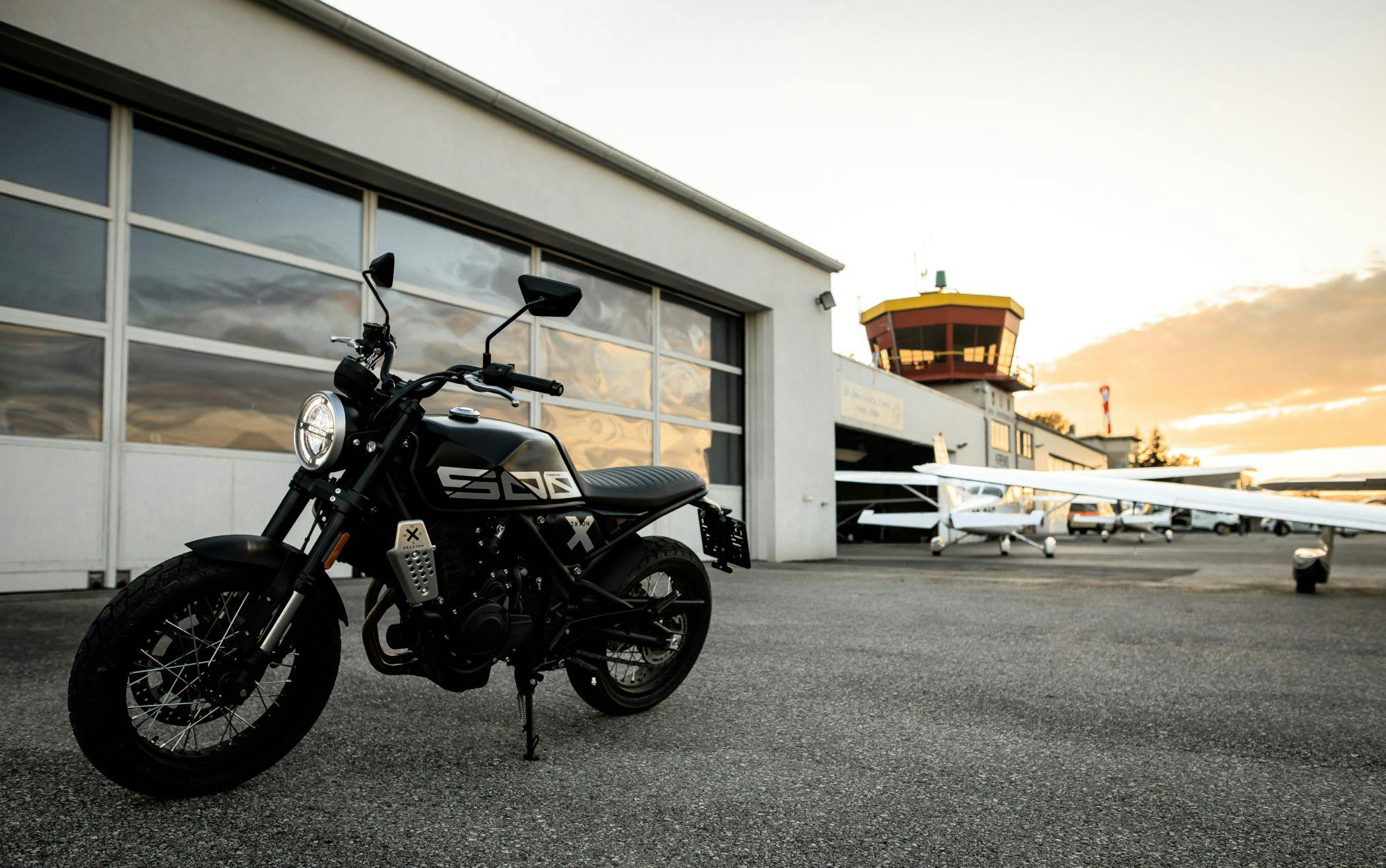 Brixton Crossfire 500 X in Backstage Black parked on an airfield in front of a hangar
