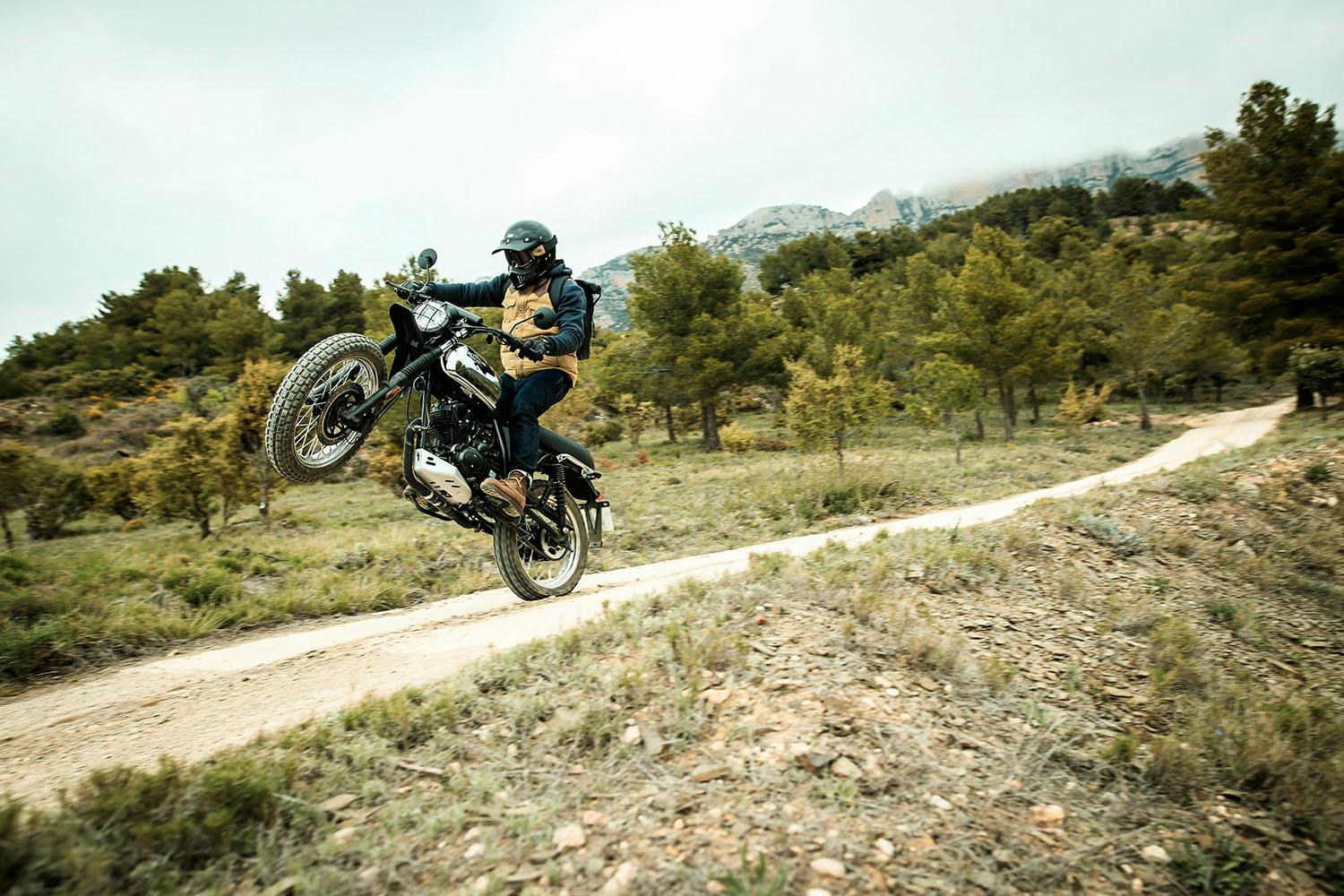 Motorcycle rider doing a wheelie with a Brixton Felsberg 125 XC in Quick Silver 