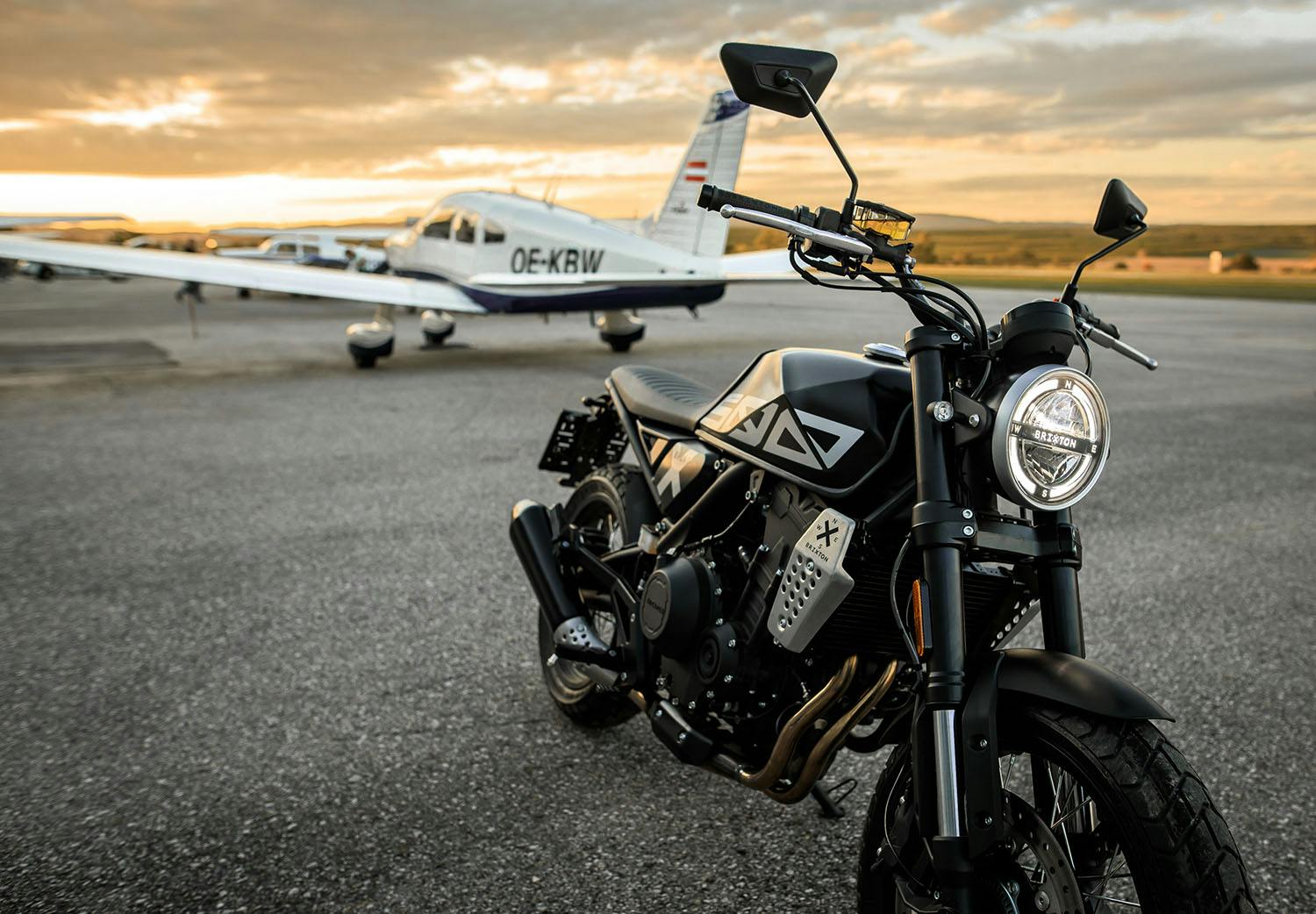 Brixton Crossfire 500 X in Backstage Black on an airfield in front of an aeroplane