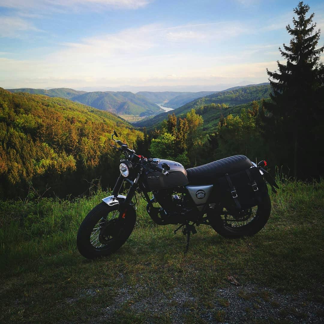Rider of the Month Robert's Brixton Cromwell 125 in Backstage Black standing in front of a picturesque mountain view