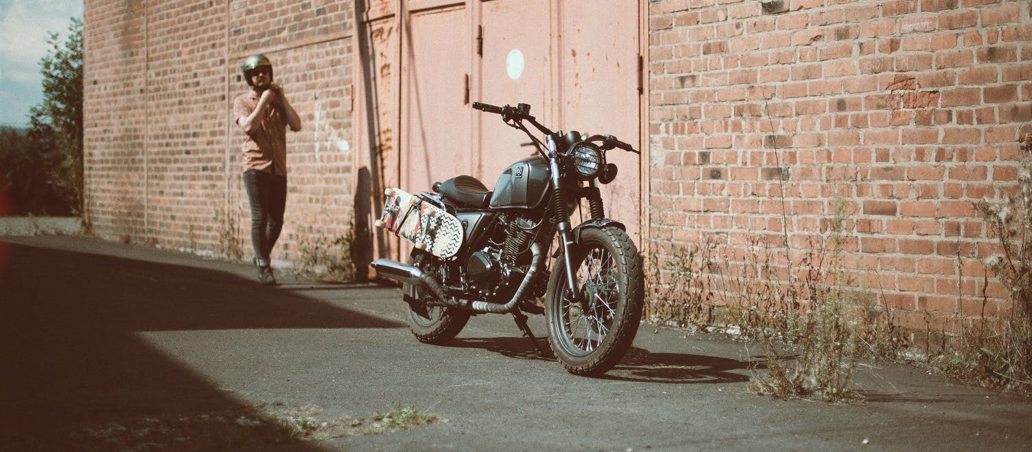 Rider of the Month Sidney's Brixton Cromwell 125 in Timberwolf Grey parked in front of a brick building