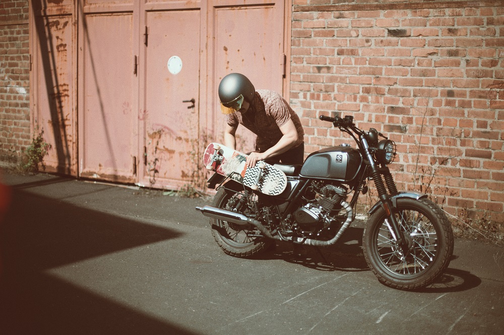 Rider of the Month Sidney storing his skateboard on his Brixton Cromwell 125 in Timberwolf Grey