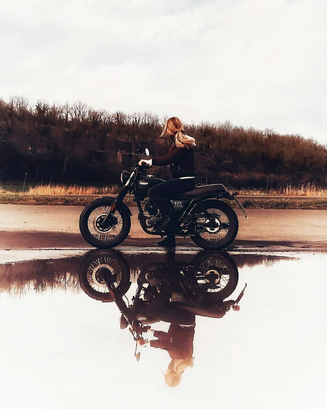 Rider of the Month Joss on her Cromwell 125 in Backstage Black that is mirrored in a puddle