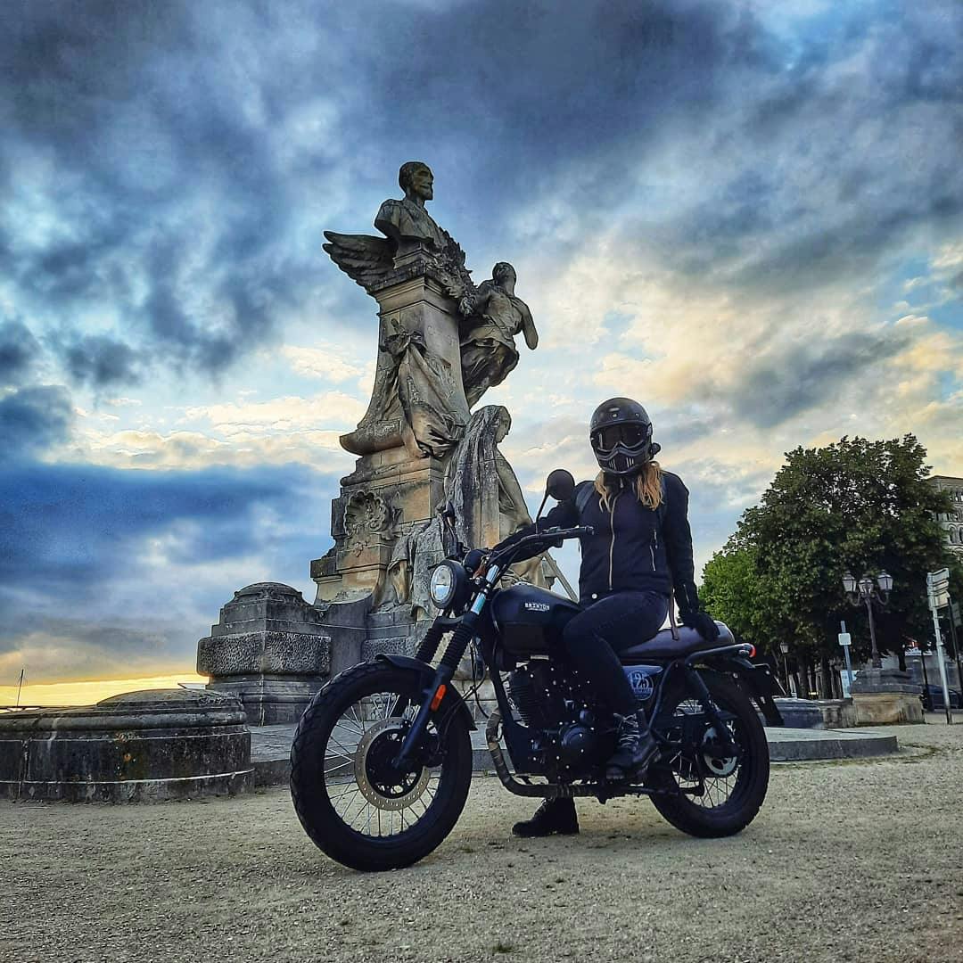 Rider of the Month Joss on her Cromwell 125 in Backstage Black in front of a baroque statue