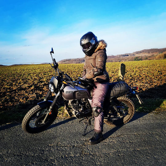 Photo of Rider of the Month Veronika on her Felsberg 125 in Timberwolf Grey parked next to a field