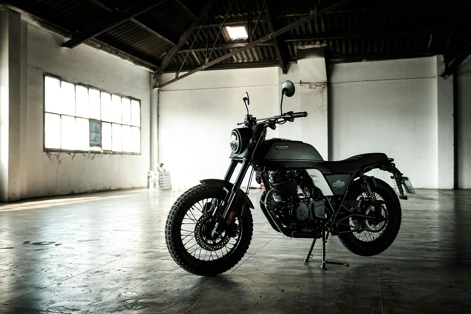 Seitenansicht einer Brixton Motorcycles Felsberg 250 in Timberwolf Grey geparkt in einer leeren Garage